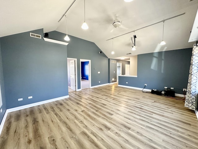 interior space featuring lofted ceiling, visible vents, track lighting, wood finished floors, and baseboards