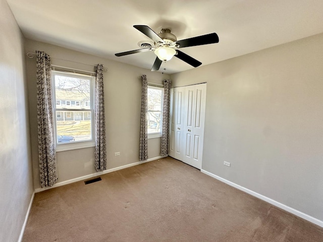 unfurnished room featuring a ceiling fan, carpet, visible vents, and baseboards