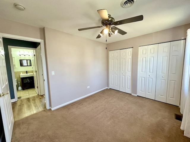 unfurnished bedroom featuring carpet, visible vents, baseboards, and two closets