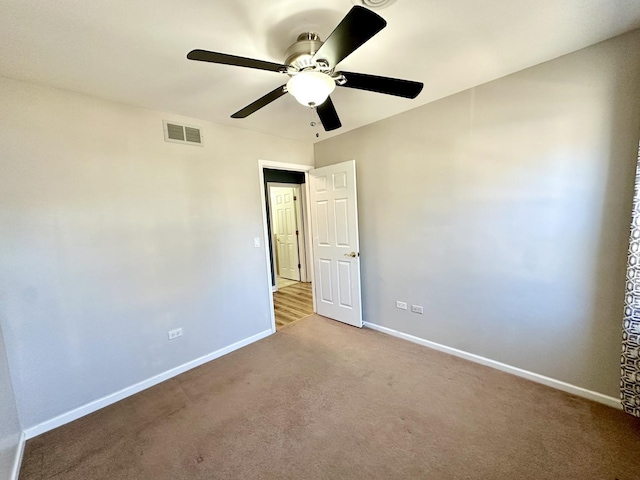 carpeted empty room featuring ceiling fan, visible vents, and baseboards