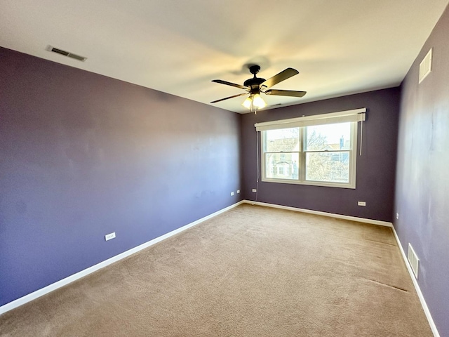 carpeted spare room with baseboards, visible vents, and a ceiling fan