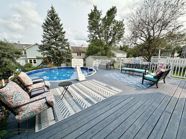 view of pool with a fenced in pool, a storage shed, fence, an outdoor structure, and a wooden deck