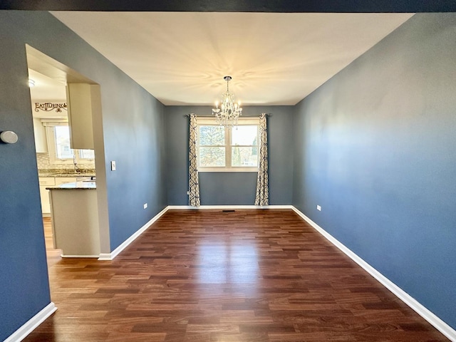 unfurnished dining area with wood finished floors, a wealth of natural light, and baseboards