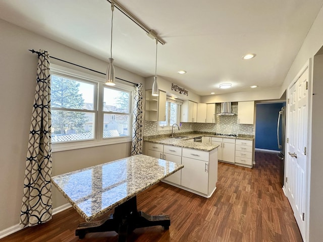 kitchen featuring tasteful backsplash, dark wood-style flooring, white cabinets, and wall chimney range hood