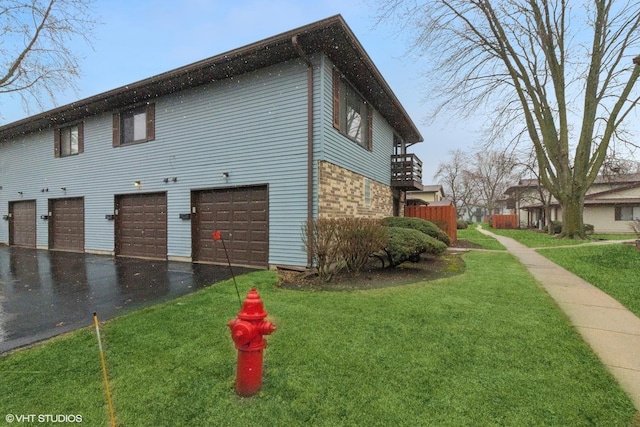 view of side of home with a garage, a yard, and aphalt driveway