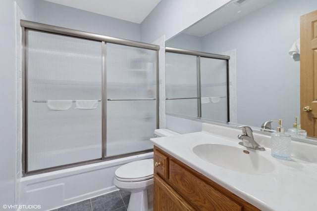 full bath with tile patterned flooring, shower / bath combination with glass door, vanity, and toilet