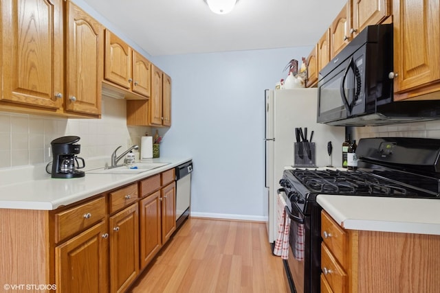 kitchen featuring light wood-type flooring, light countertops, a sink, and black appliances