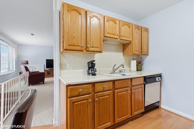 kitchen featuring light countertops, a sink, backsplash, and dishwasher