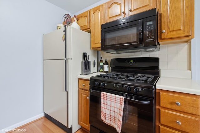 kitchen featuring black appliances, light countertops, and backsplash