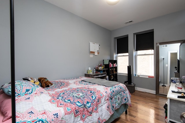 bedroom with wood finished floors, visible vents, and baseboards