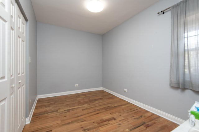 unfurnished bedroom with a closet, baseboards, and wood finished floors