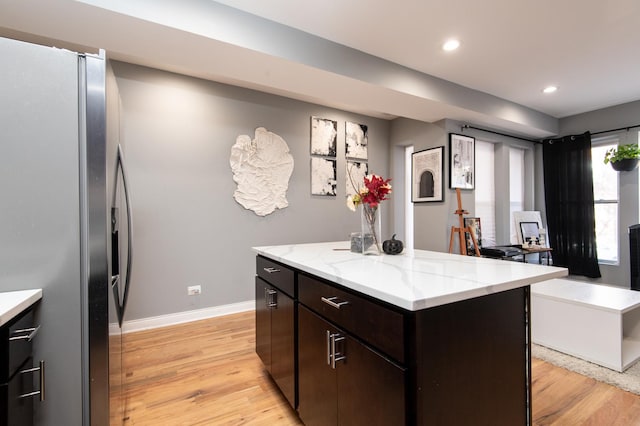 kitchen featuring recessed lighting, a kitchen island, baseboards, light wood-type flooring, and stainless steel refrigerator with ice dispenser