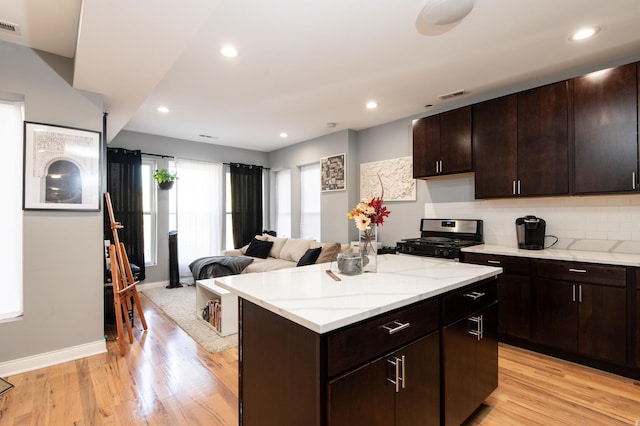 kitchen featuring a kitchen island, light wood-type flooring, stainless steel range with gas cooktop, and visible vents