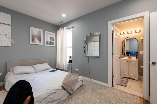 bedroom with a sink, connected bathroom, visible vents, and baseboards