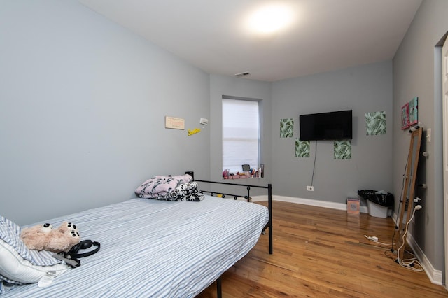 bedroom featuring visible vents, baseboards, and wood finished floors