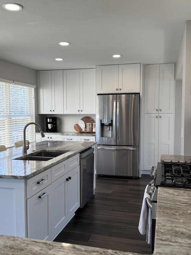 kitchen with stainless steel appliances, dark wood-style flooring, white cabinets, and a sink