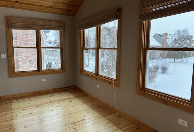 spare room featuring lofted ceiling, light wood-style floors, baseboards, and wooden ceiling