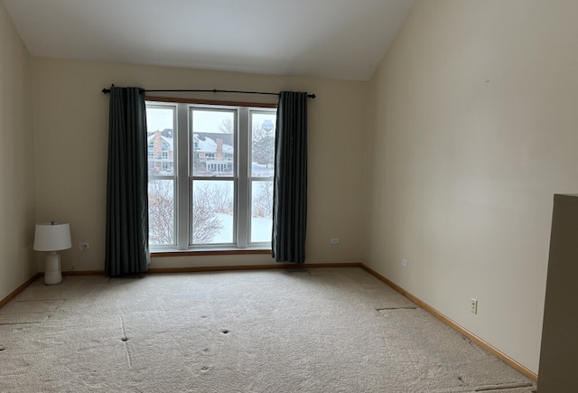 carpeted empty room featuring lofted ceiling and baseboards