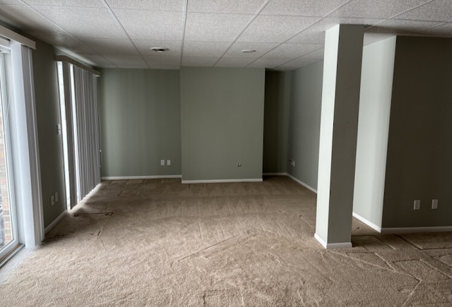 carpeted empty room with a paneled ceiling and baseboards