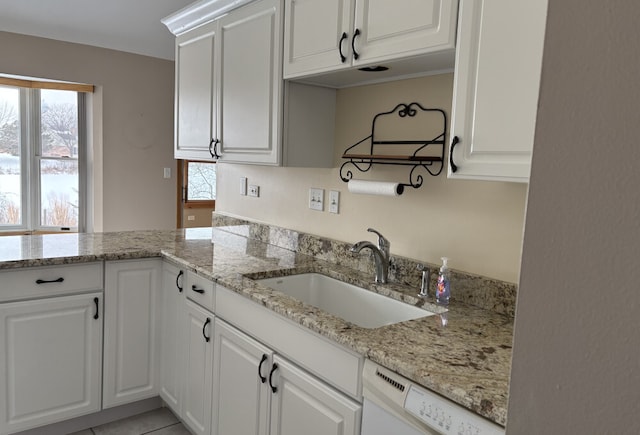 kitchen featuring light stone countertops, dishwasher, white cabinets, and a sink