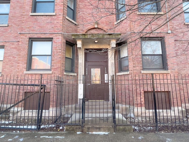 view of exterior entry with brick siding and fence