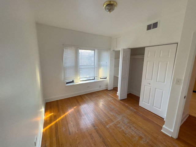 unfurnished bedroom featuring hardwood / wood-style flooring, baseboards, and visible vents