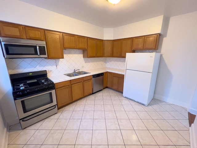 kitchen featuring stainless steel appliances, brown cabinetry, a sink, and tasteful backsplash