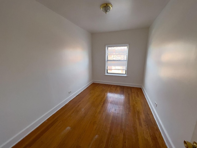 unfurnished room with hardwood / wood-style flooring and baseboards