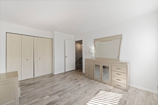 unfurnished bedroom featuring light wood-style flooring, baseboards, and a closet