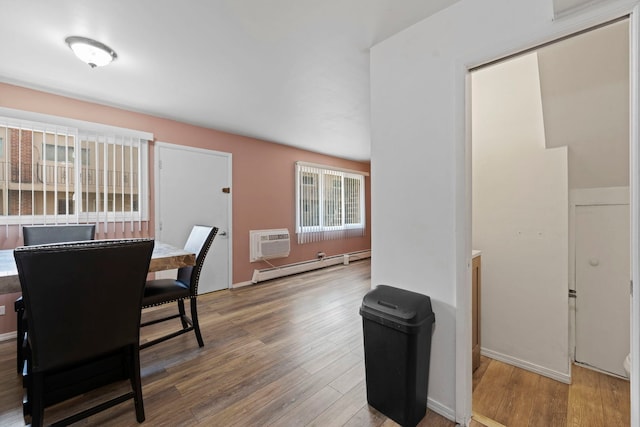 dining area with a wall unit AC, a baseboard radiator, and wood finished floors