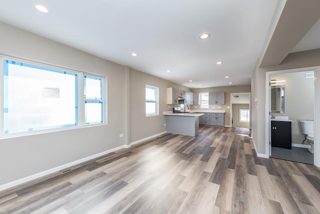 interior space featuring baseboards, light countertops, wood finished floors, and recessed lighting