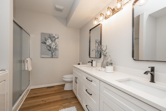 full bathroom featuring toilet, wood finished floors, a shower stall, and a sink