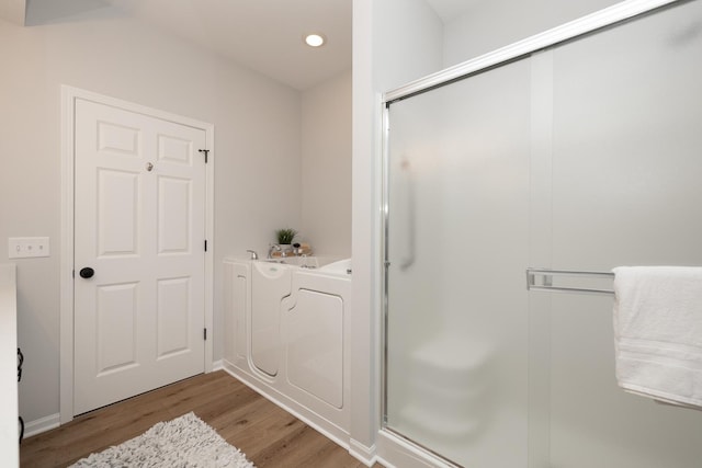 full bathroom with a shower stall, a bath, wood finished floors, and recessed lighting