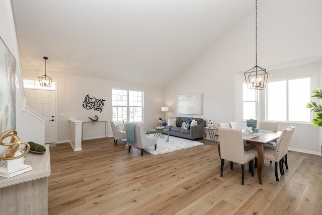 dining room featuring light wood-style flooring, high vaulted ceiling, and an inviting chandelier