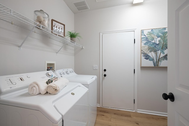 washroom with light wood finished floors, visible vents, baseboards, washing machine and dryer, and laundry area