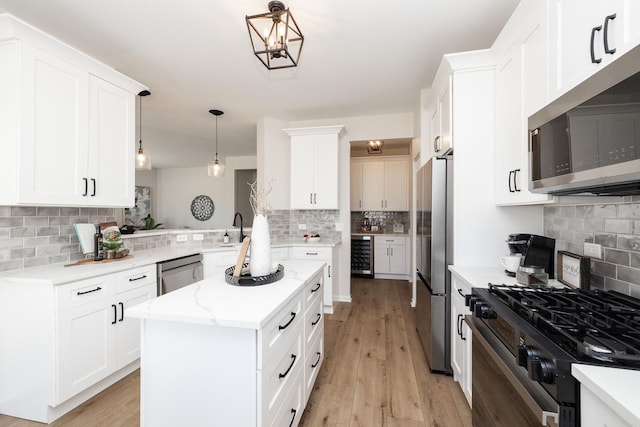 kitchen with a kitchen island, light wood-style flooring, decorative backsplash, wine cooler, and appliances with stainless steel finishes