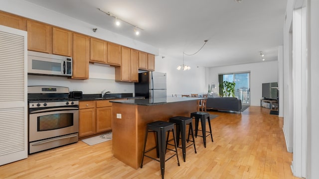 kitchen with a breakfast bar, a kitchen island, open floor plan, light wood-style floors, and appliances with stainless steel finishes