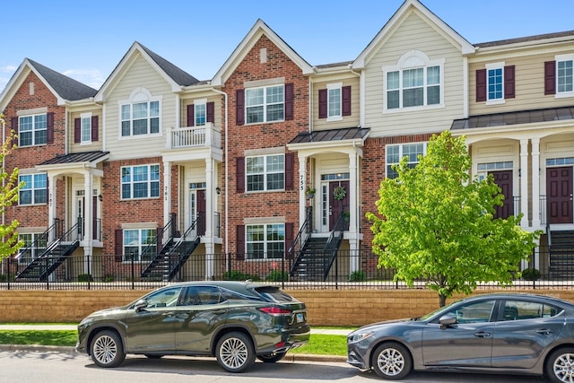 multi unit property featuring a fenced front yard, a standing seam roof, and brick siding