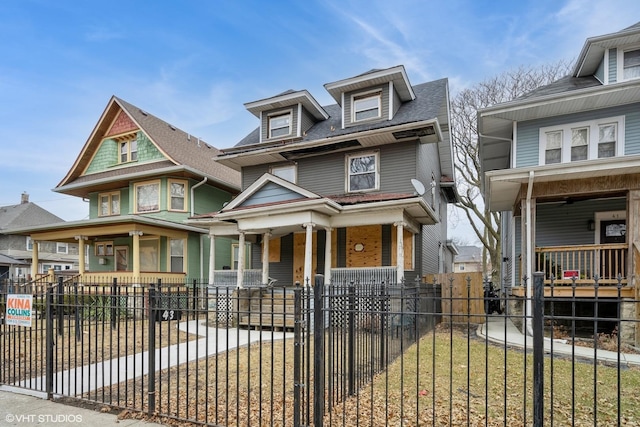 view of front facade with covered porch, driveway, and a fenced front yard