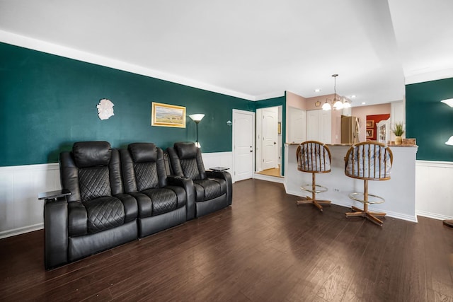 living area with a wainscoted wall, dark wood-type flooring, and a notable chandelier