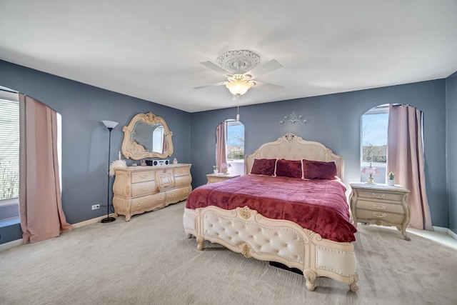 carpeted bedroom with a ceiling fan, multiple windows, and baseboards