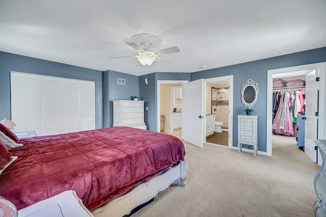 bedroom with baseboards, visible vents, light colored carpet, ensuite bathroom, and a closet