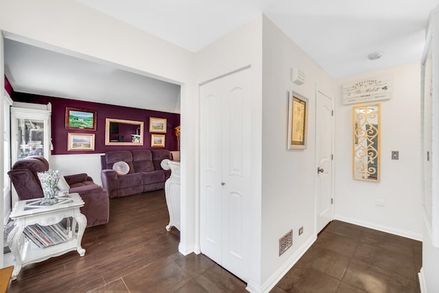 hall with visible vents, dark wood finished floors, and baseboards