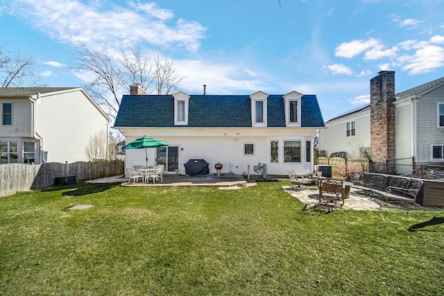 back of property with an outdoor fire pit, a patio, a lawn, and mansard roof