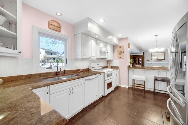 kitchen featuring backsplash, glass insert cabinets, white cabinetry, a sink, and white appliances