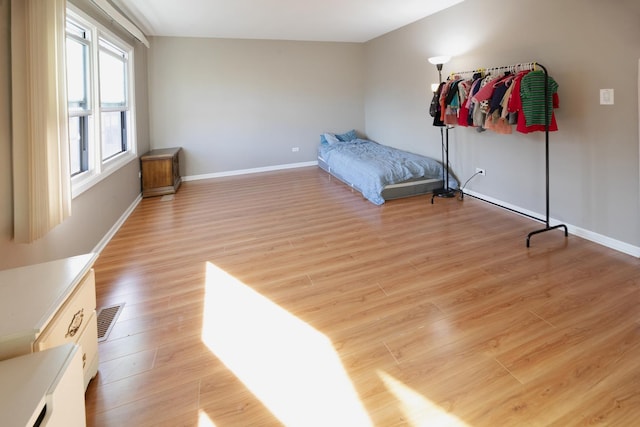 bedroom featuring light wood-type flooring, visible vents, and baseboards