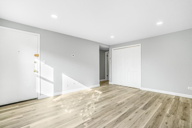 empty room with light wood-type flooring, baseboards, and recessed lighting