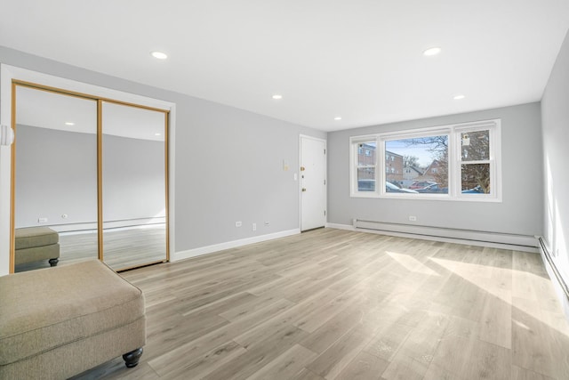 unfurnished living room with a baseboard radiator, baseboards, light wood-style flooring, and recessed lighting