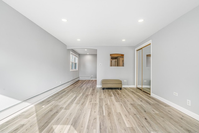 spare room featuring a baseboard heating unit, light wood finished floors, recessed lighting, and baseboards