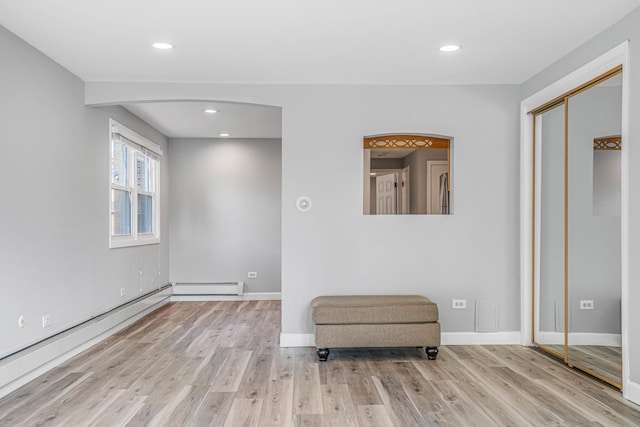 unfurnished room featuring a baseboard heating unit, baseboards, wood finished floors, and recessed lighting